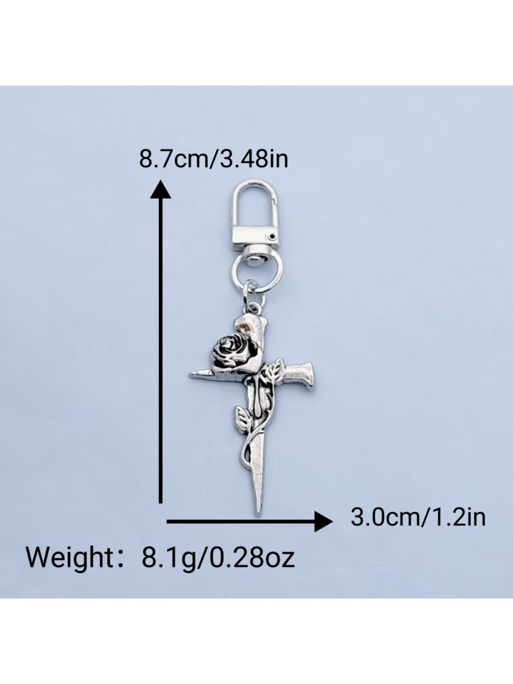 Rose cross keychain attached to a set of keys on a wooden surface