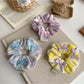 Gifty Ribbon Bow Plaid Scrunchie displayed on a wooden surface with natural lighting