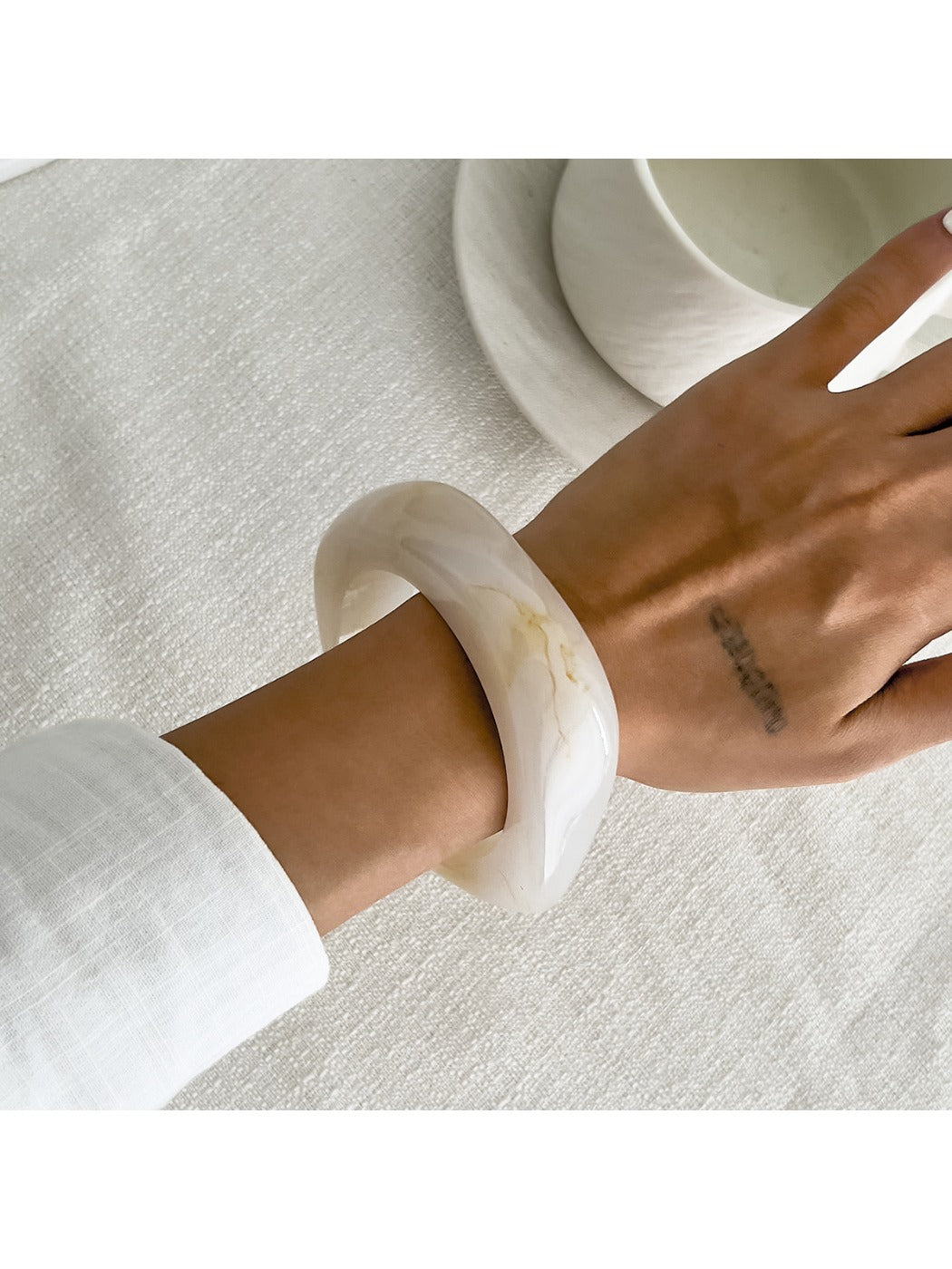 Lovra asymmetrical bangle bracelet paired with matching rings on hand