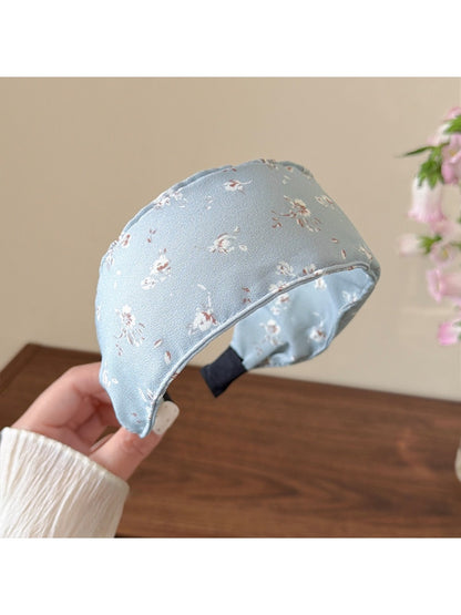 Headband displayed on a wooden surface highlighting its soft fabric and floral design
