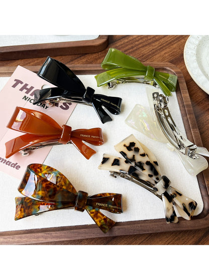 Beau hair clip open to show metal clasp mechanism and acetate bow