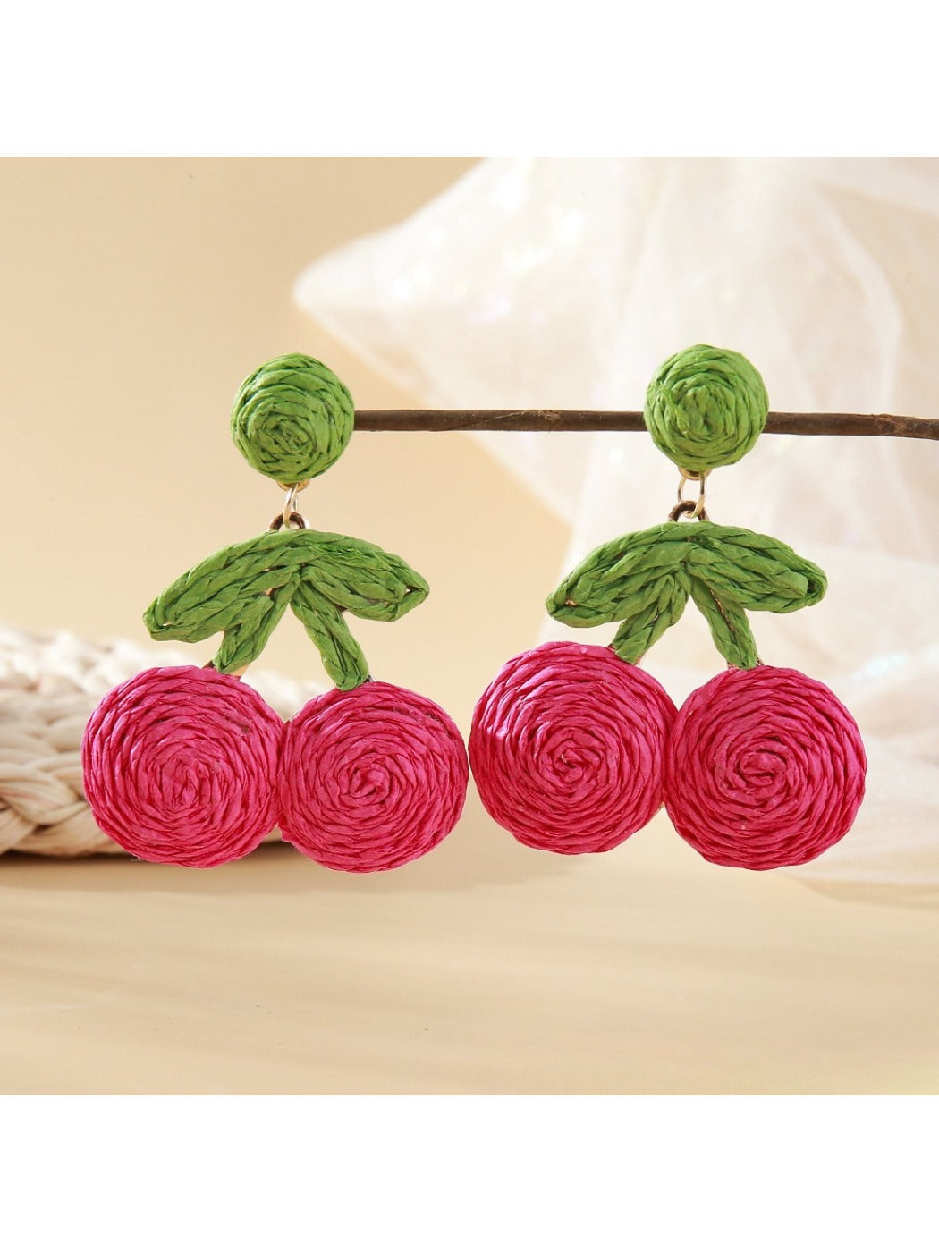 Raffia woven cherry earrings shown from above on a neutral background