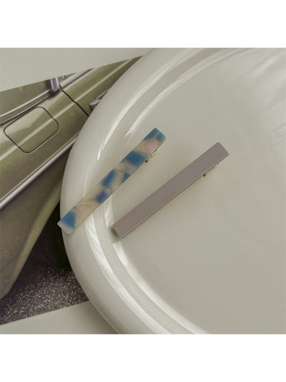 Beau hair clip positioned on fabric surface emphasizing smooth acetate texture