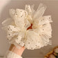 White tulle scrunchie with black polka dots on a plain background