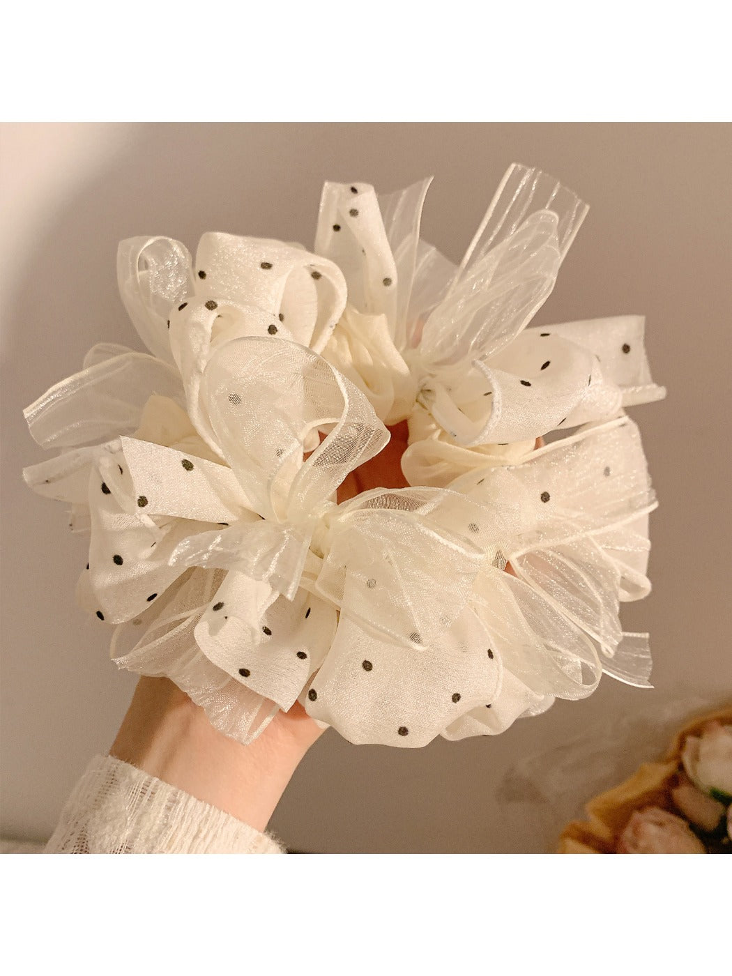 White tulle scrunchie with black polka dots on a plain background