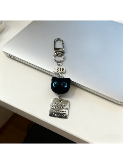 Side view of blue eyed black cat keychain highlighting its compact size