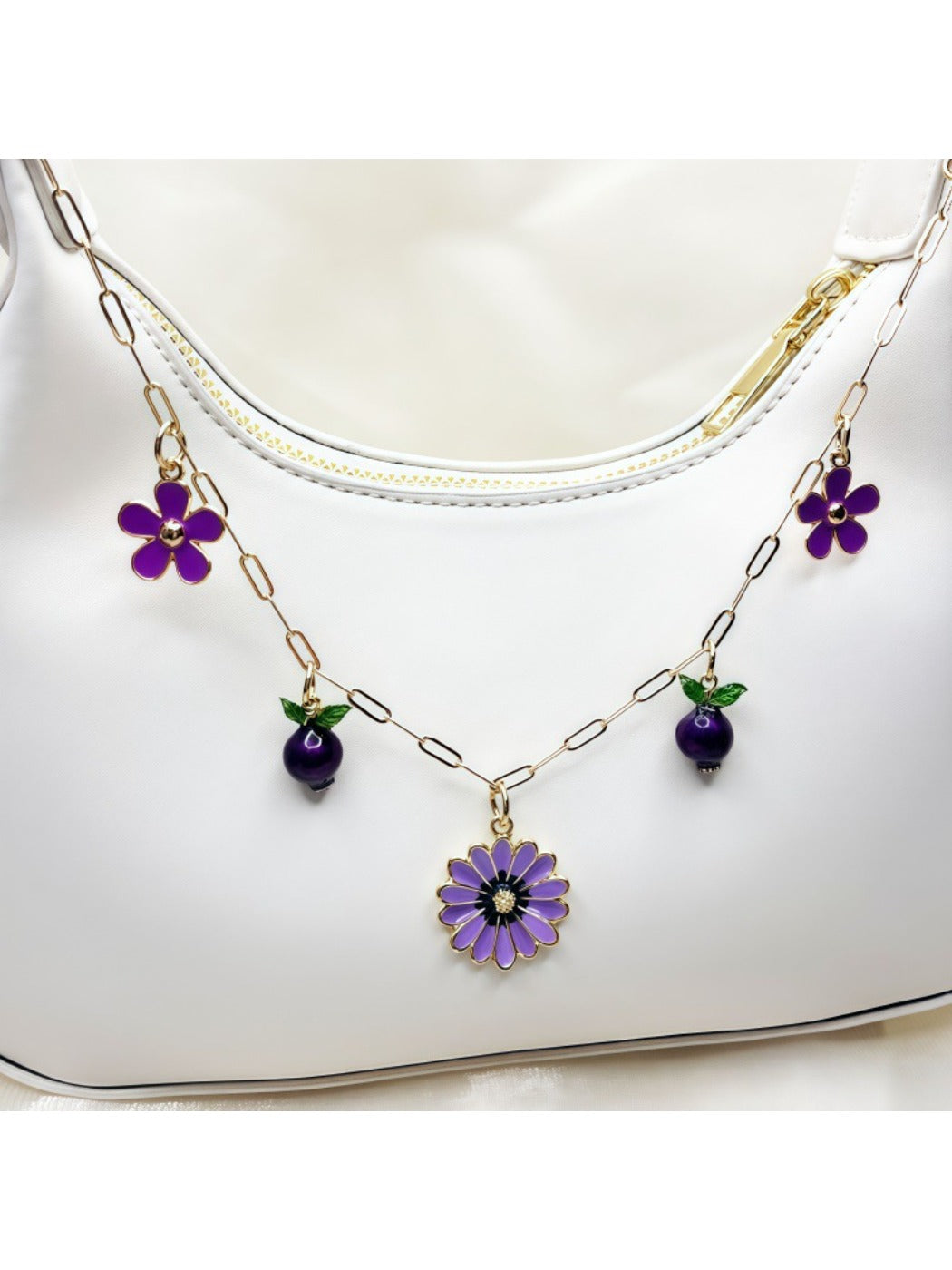 Daisy pendant bag charm hanging from a beige handbag strap