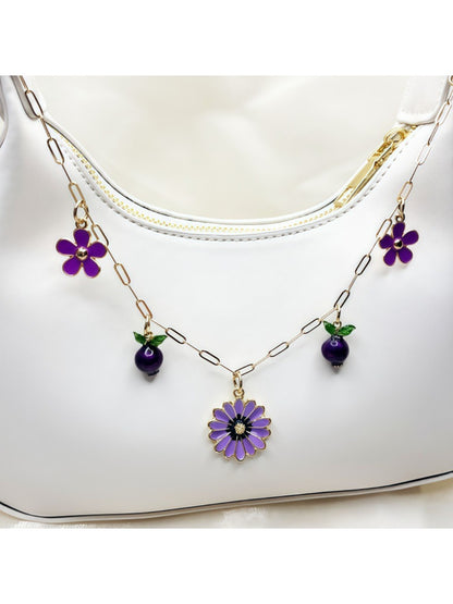 Daisy pendant bag charm hanging from a beige handbag strap