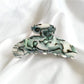 Beau vintage acetate claw clip resting on wooden surface with soft shadows