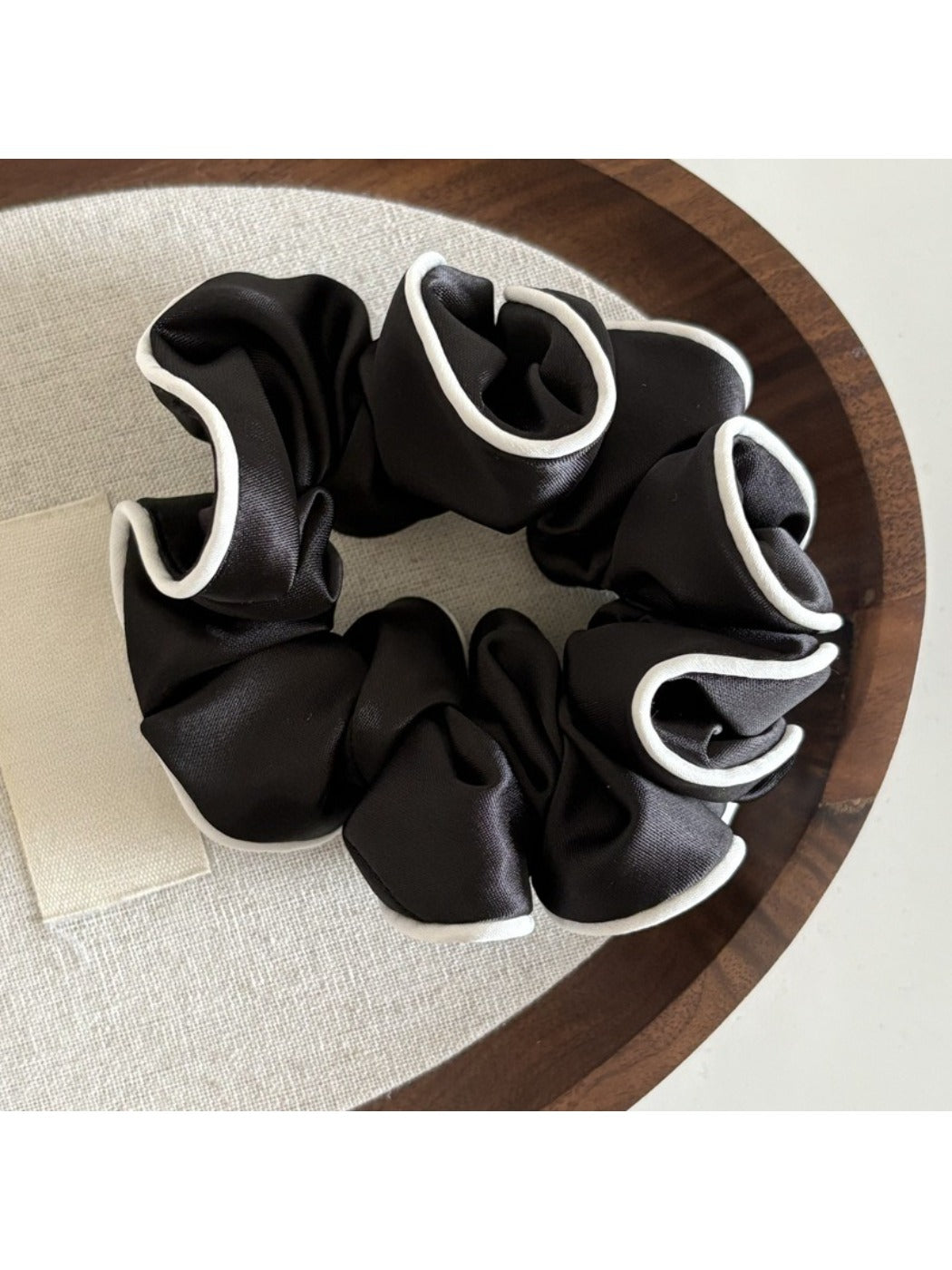 Top view of ruffled satin scrunchie highlighting smooth fabric and elastic band