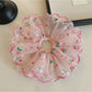 Pink ruffled scrunchie displayed flat showing texture and layers