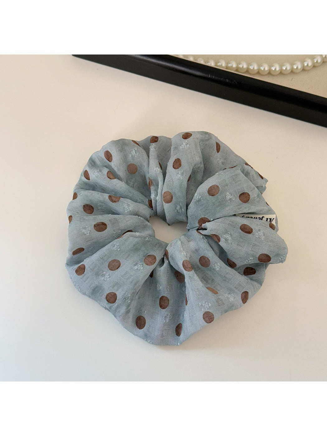 Blue polka dot headband and scrunchie set styled on a wooden table
