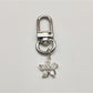 Keypus flower charm keychain placed next to a smartphone and wallet on a table