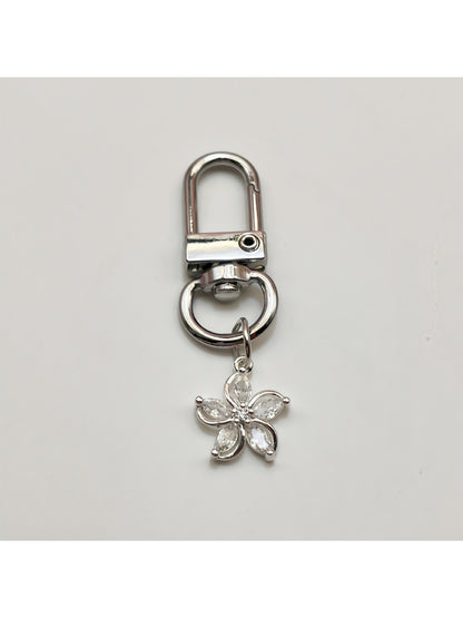 Keypus flower charm keychain placed next to a smartphone and wallet on a table