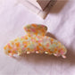 Beau chic tiny floral acetate claw clip photographed with soft shadows