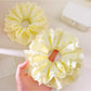 Close-up of Gifty sweet yellow ruffle scrunchie with soft fabric texture