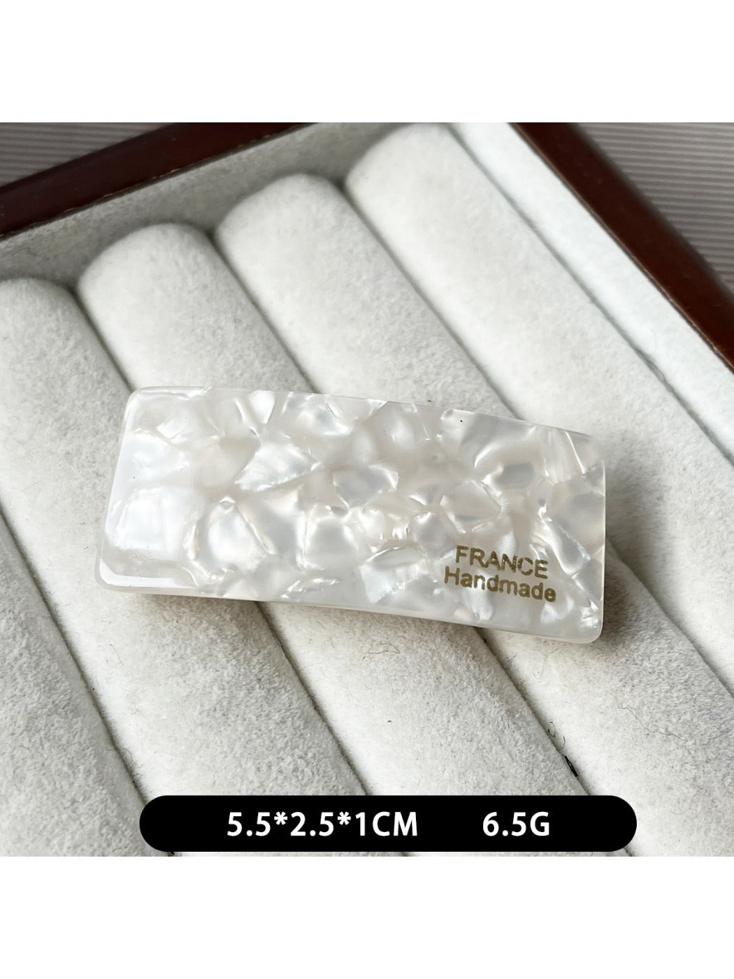 Beau curved bar hair clip resting on a marble countertop
