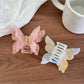 Close-up of pastel pink butterfly claw clip showing detailed wings