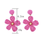 Pair of Earedge floral raffia woven vintage drop earrings displayed on a wooden surface