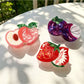 Beau lifelike fruit claw clip shaped like a peach with green leaves