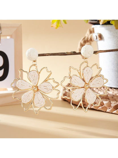 Earedge flower shaped drop earrings hanging from a jewelry stand