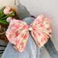 Red floral bow scrunchie paired with casual outfit on model