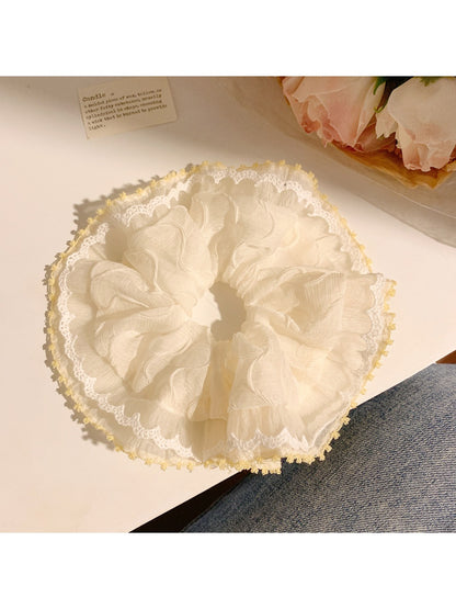 Gifty scrunchie held in hand highlighting its stretch and fabric detail