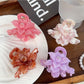 Side view of beige lotus shaped hair claw clip highlighting spring mechanism
