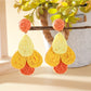 Earedge raffia drop earrings paired with matching accessories on a textured surface