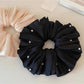 Beige satin scrunchie displayed flat showing its full size and shape
