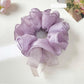 Elegant purple bow scrunchie made of soft fabric on a white background