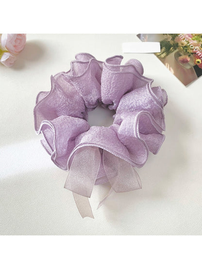 Elegant purple bow scrunchie made of soft fabric on a white background