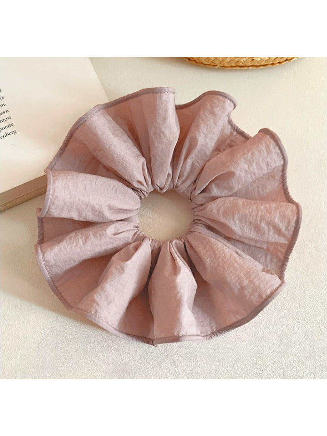 Soft pink scrunchie displayed on a wooden surface with natural lighting