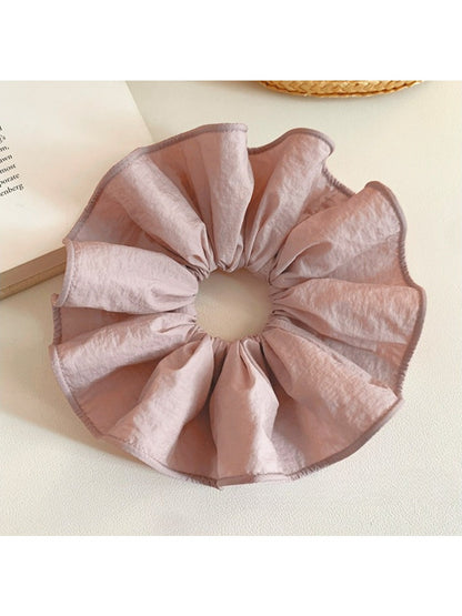 Soft pink scrunchie displayed on a wooden surface with natural lighting