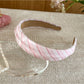 Flat lay of Gifty headband with beige plaid and white stripes on neutral surface