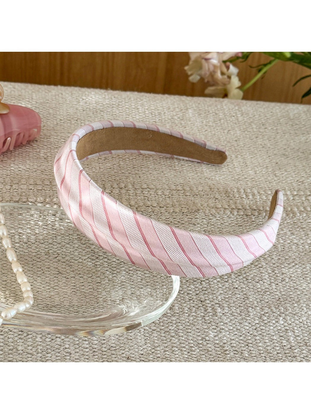 Flat lay of Gifty headband with beige plaid and white stripes on neutral surface