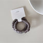 Close-up of satin fabric texture on Gifty minimalist hair tie in soft lighting