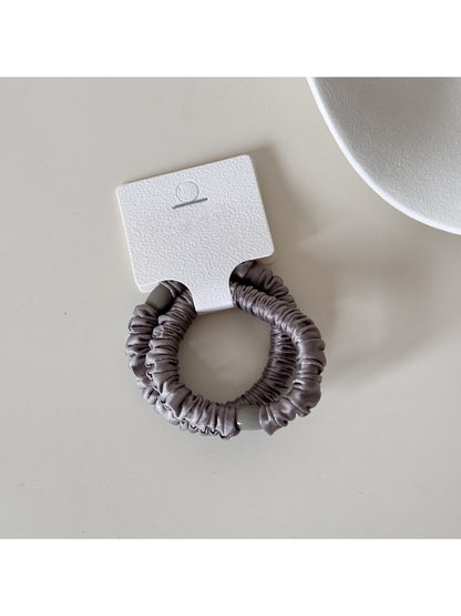 Close-up of satin fabric texture on Gifty minimalist hair tie in soft lighting