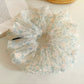 Side view of large green tulle scrunchie with tiny floral details