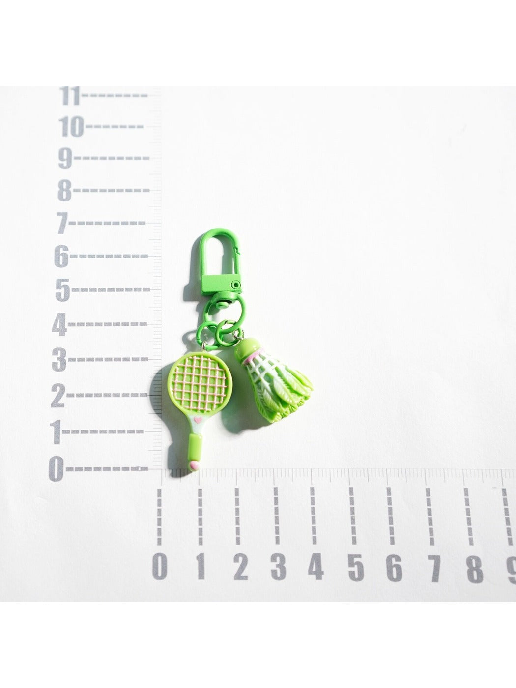 Badminton racket keychain attached to a set of keys on a wooden surface
