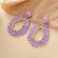 Earedge raffia teardrop hollow earrings placed next to green leaves