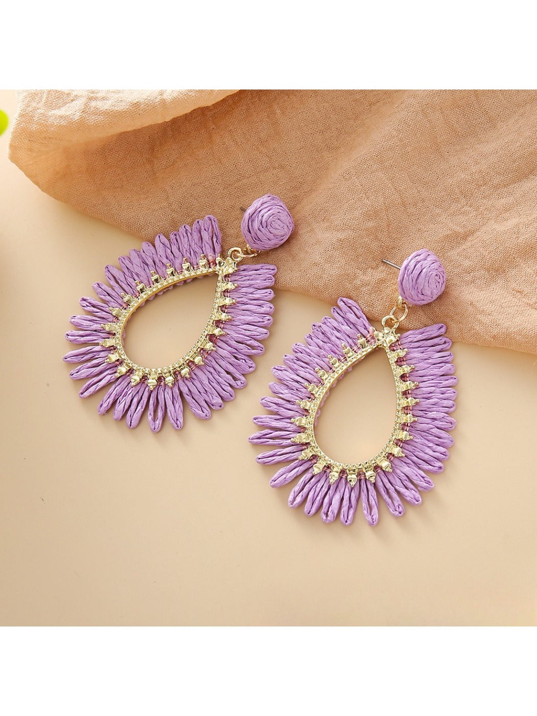 Earedge raffia teardrop hollow earrings placed next to green leaves