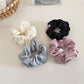 Top view of a beige satin bow scrunchie showing its smooth texture and bow detail