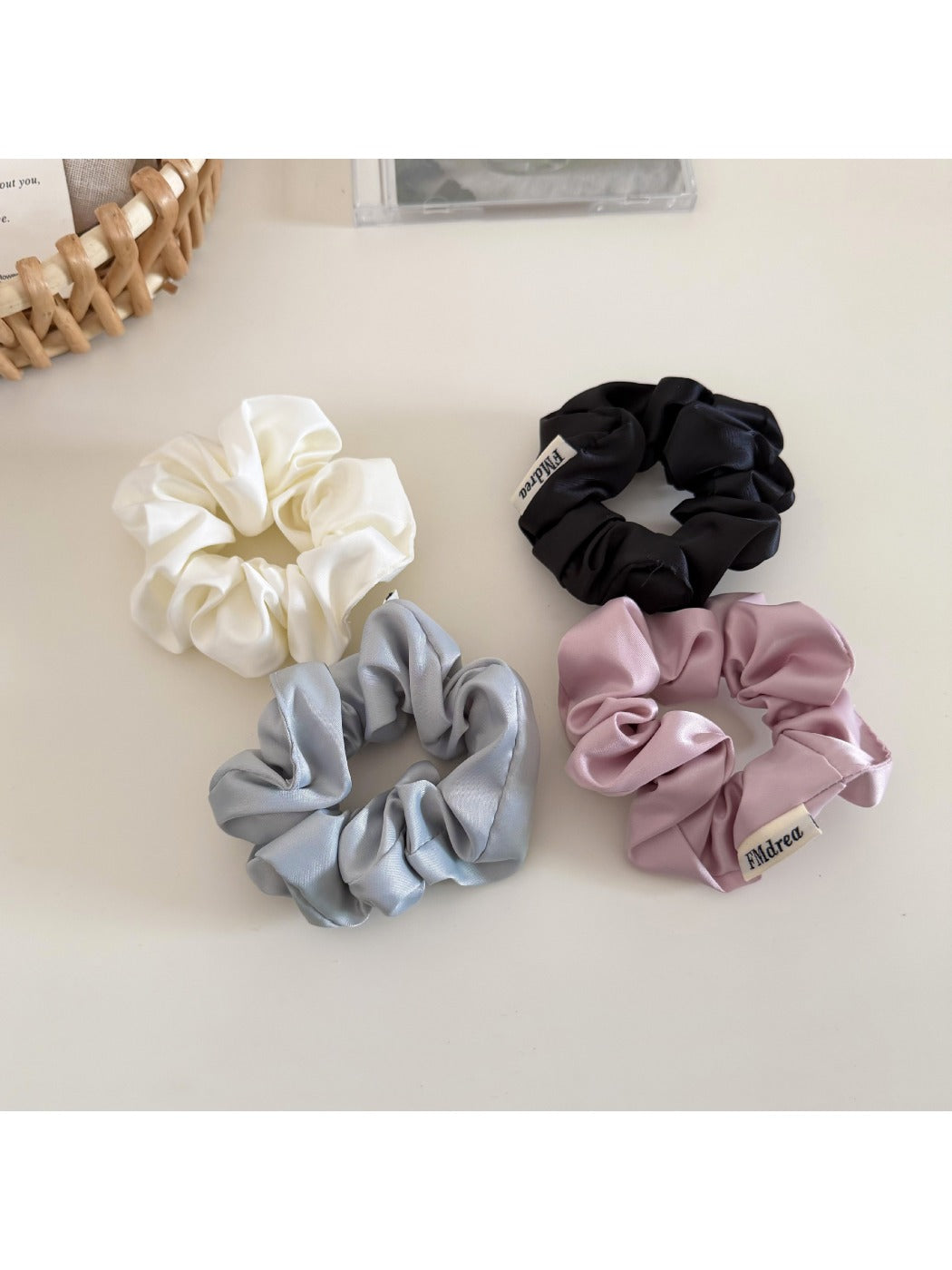 Top view of a beige satin bow scrunchie showing its smooth texture and bow detail