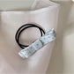 Model styling hair with Gifty pink bow embellished hair tie in natural light