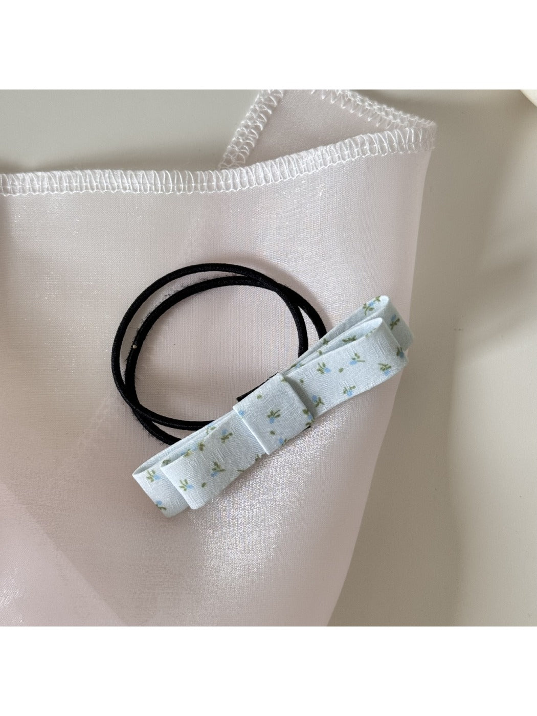 Model styling hair with Gifty pink bow embellished hair tie in natural light