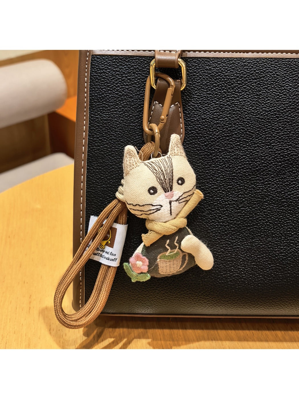 Vintage cat charm keychain hanging from a bag zipper pull