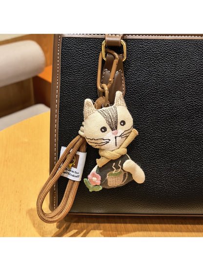 Vintage cat charm keychain hanging from a bag zipper pull