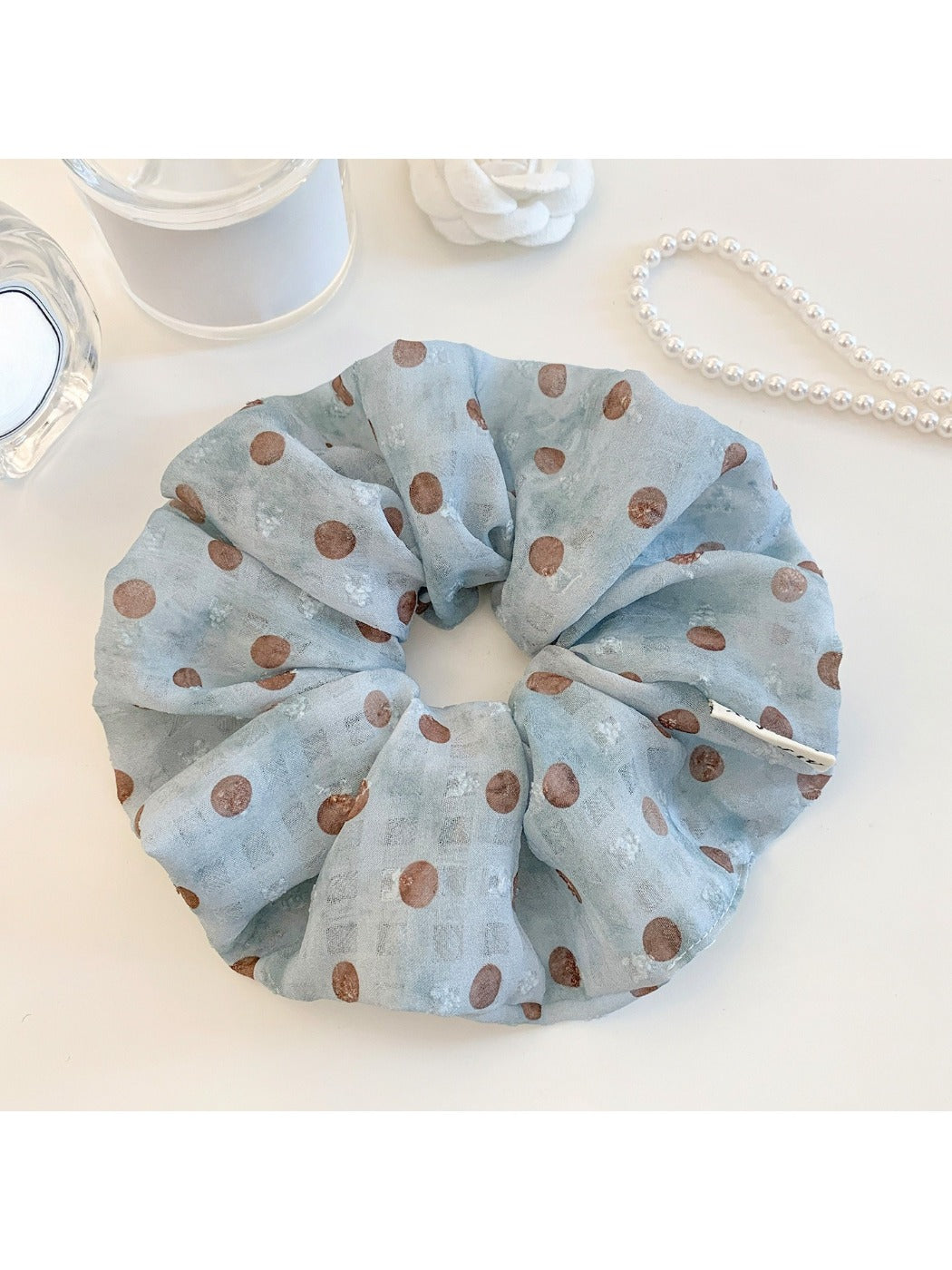 Close-up of Gifty polka dot ruched scrunchie in black and white fabric