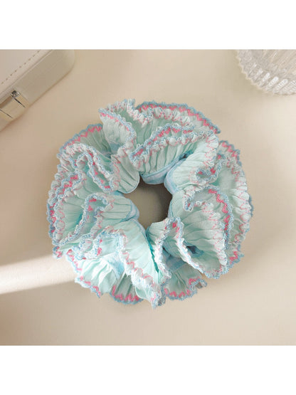 Blue ruffle scrunchie worn on a wrist as a fashion accessory